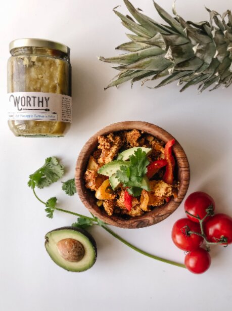 Wooden bowl of vegan tofu scramble made with Worthy's Hot Pineapple Turmeric Salsa topped with cilantro, avocado, and cherry tomatoes.