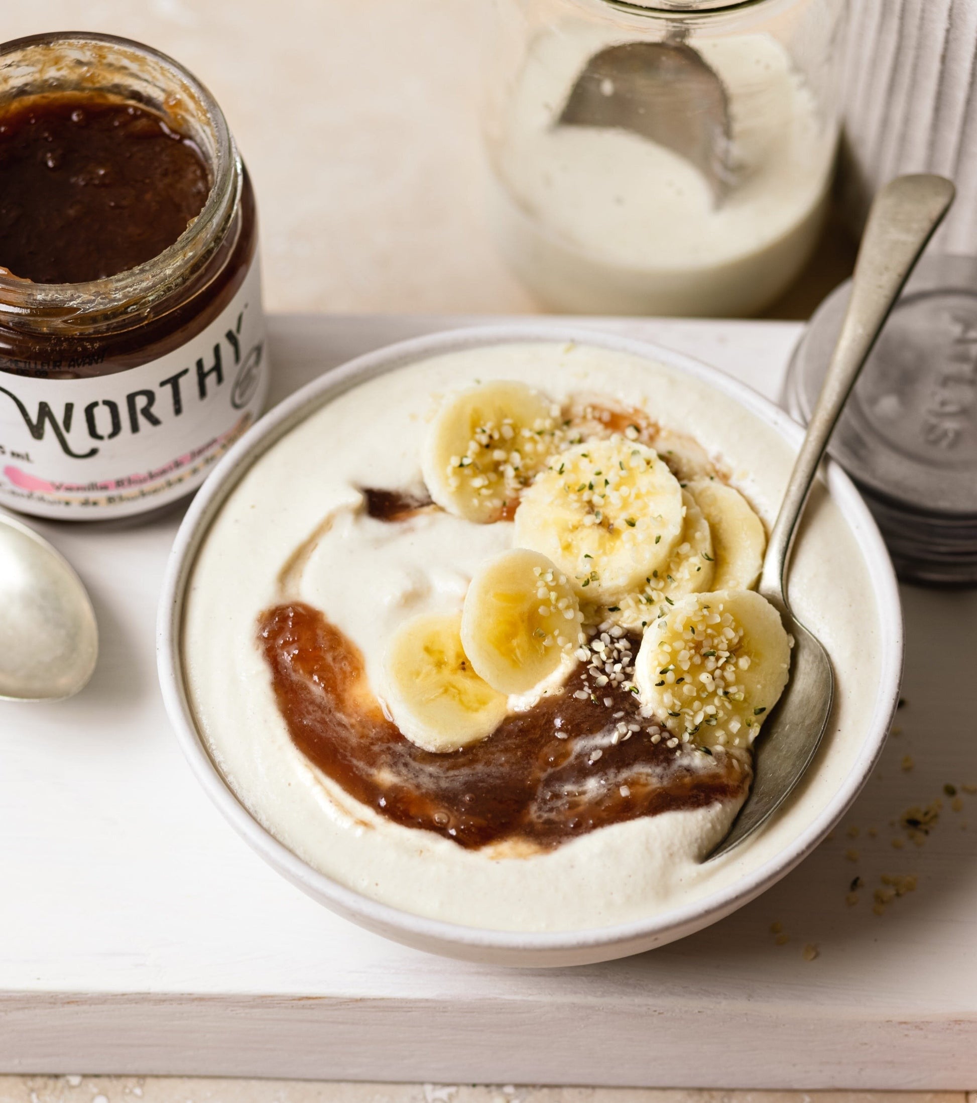 Bowl of blended cashews topped with Worthy’s Vanilla Rhubarb jam, slices of banana and hemp hearts.