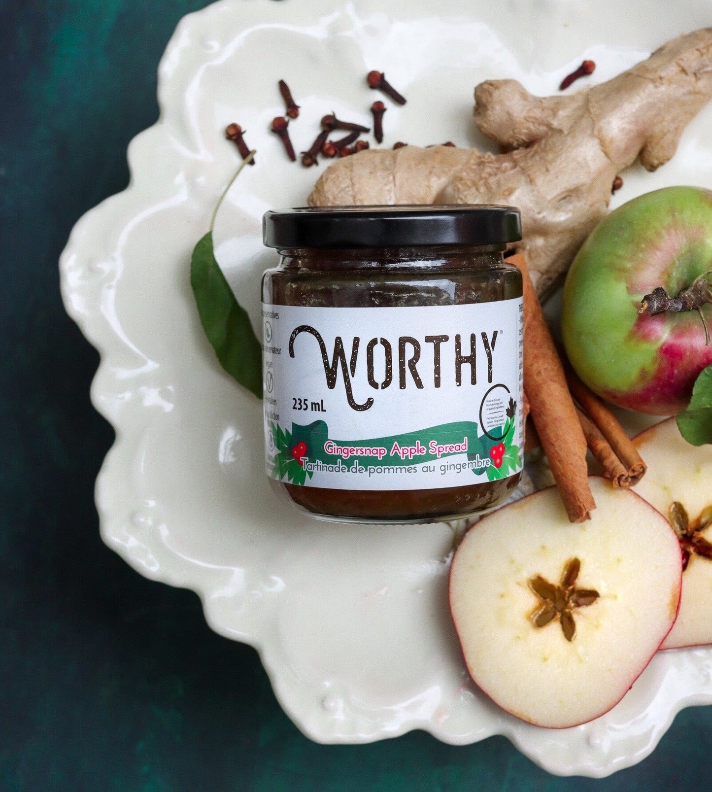 Worthy's Gingersnap Apple Spread displayed on a white plate with fresh ginger, apples, and cinnamon sticks.