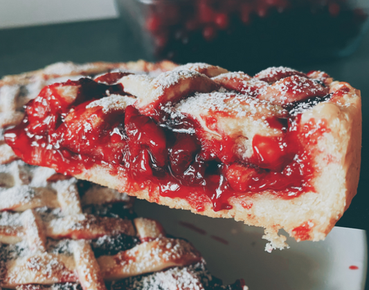 a slice of delicious bright red strawberry and rhubarb pie with powered sugar sprinked on top.