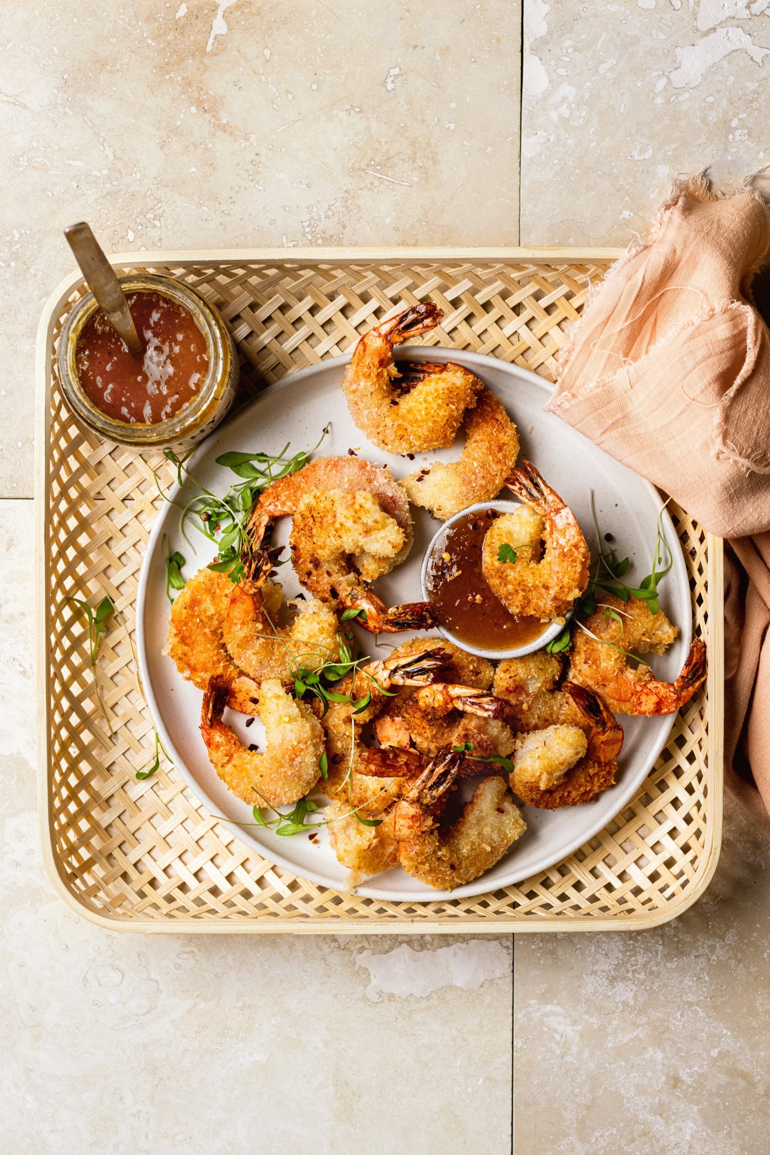 Plate of coconut-crusted shrimp with one shrimp dunked in a spicy dipping sauce made with Worthy’s Earl Grey Lavender Peach jam and red pepper flakes.
