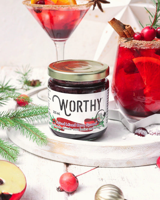 Pomegranate and berry mocktail with a cinnamon sugar rim topped with fruit and spices made with Worthy’s Spiced Mixed Berry spread in a Christmas setting.