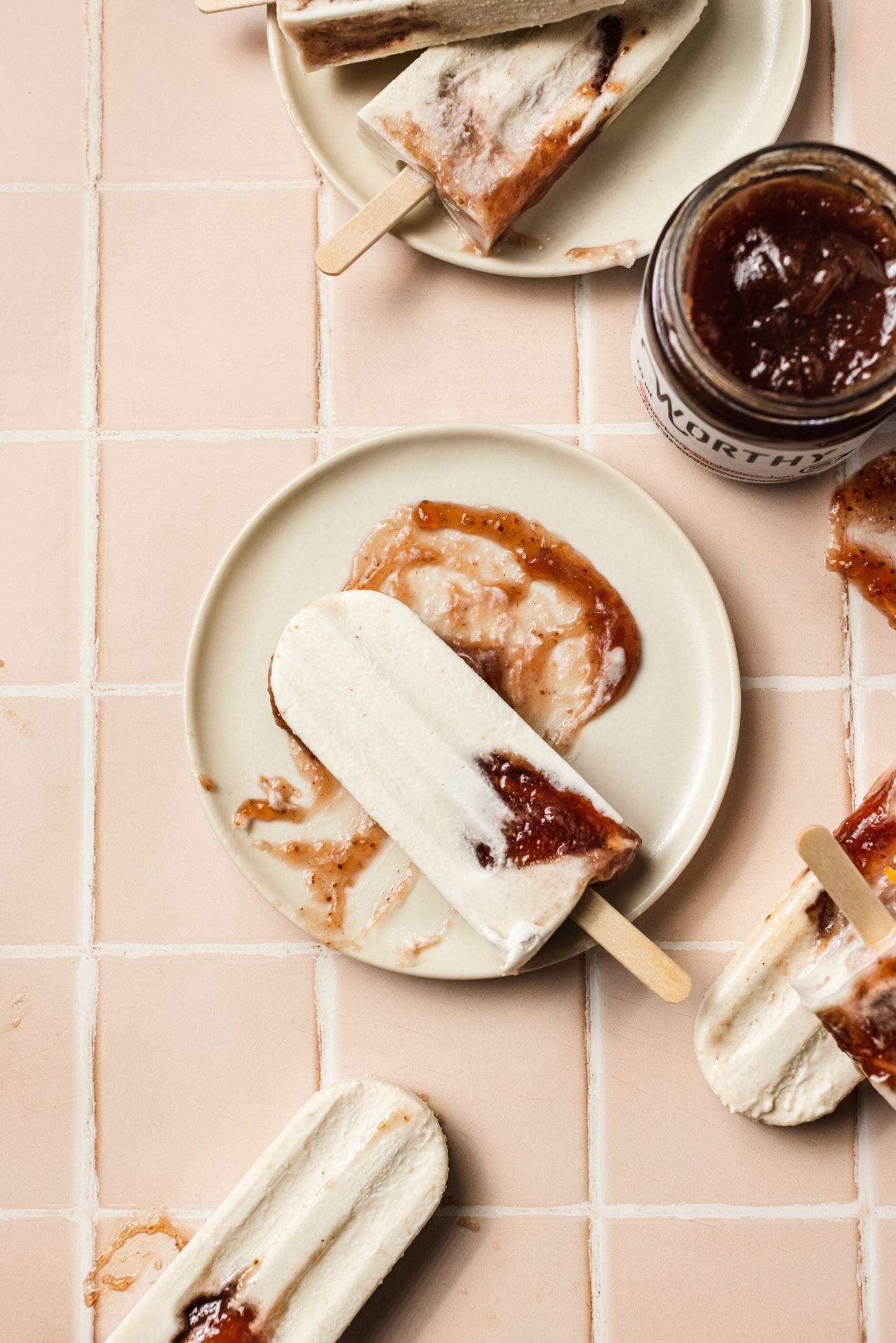 Peanut butter and coconut cream popsicle with Worthy’s Strawberry Cardamom jam oozing out while laying on its side.