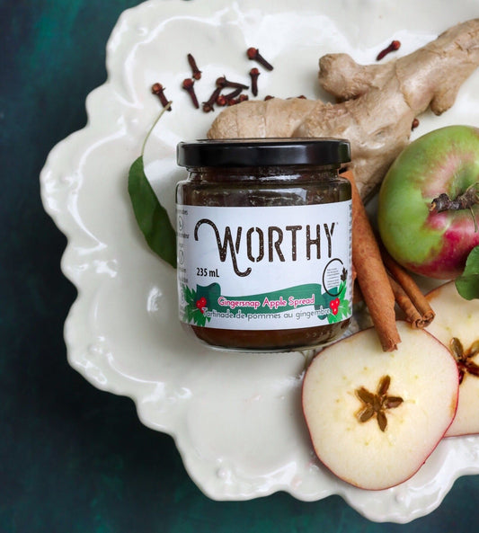  Worthy's Gingersnap Apple Spread displayed on a white plate with fresh ginger, apples, and cinnamon sticks. 