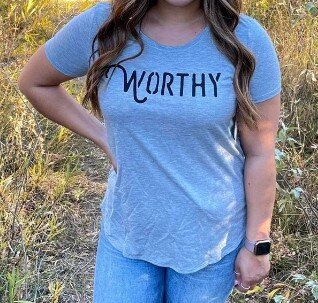 A close up of a grey t-shirt with black "WORTHY" lettering across the front.